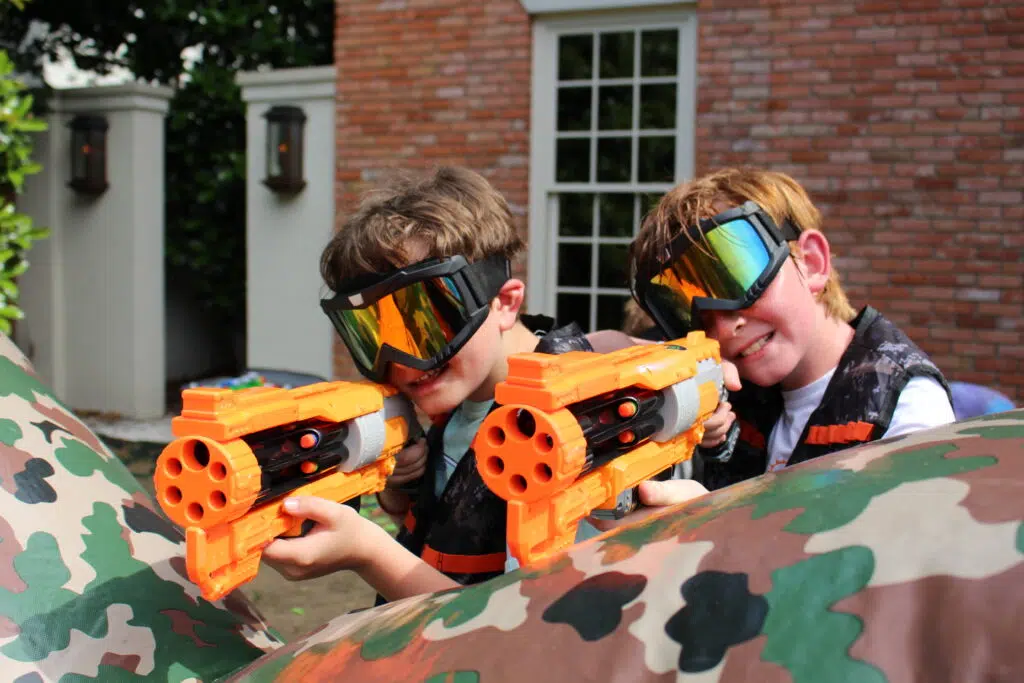 Two children teaming up behind a Nerf battlefield bunker