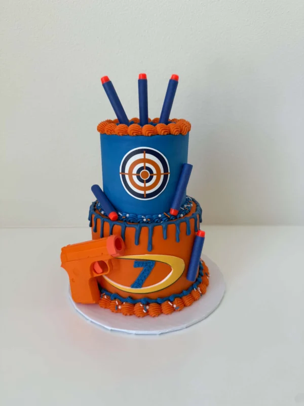 Mini two-tier Nerf-themed birthday cake with a target and dart decorations